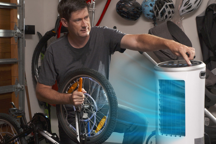 Mann in der Werkstatt bedient das mobile Luftkühlgerät mit aktiver Kühlfunktion.