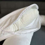 Ein weißer Dreamolino SwanPillow Kissenbezug, teilweise geöffnet, zeigt das weiche Innenkissen mit kleinen Vertiefungen.