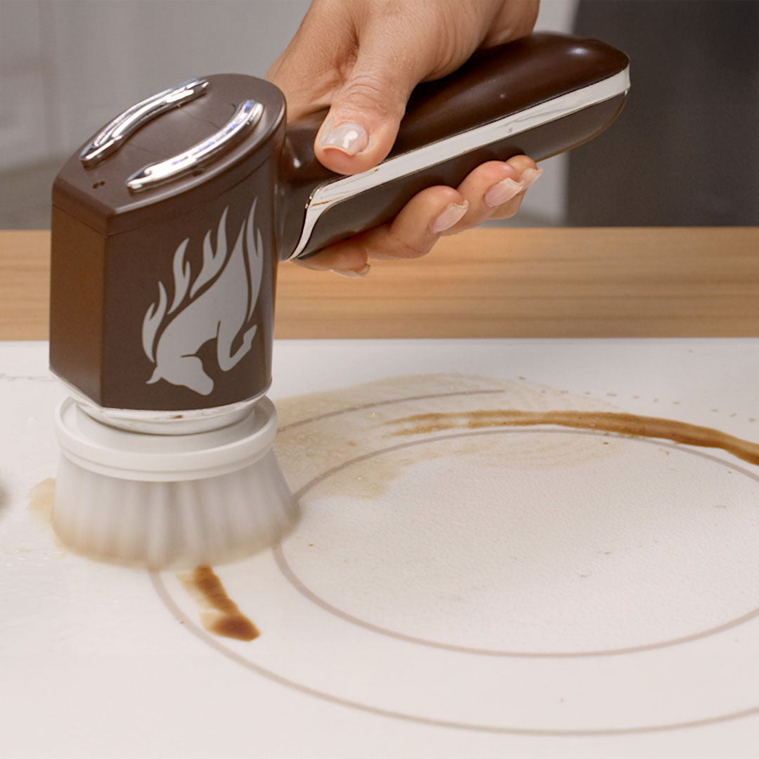 Handheld-Reinigungsbürste säubert eine verschmutzte Oberfläche mit braunen Flecken.