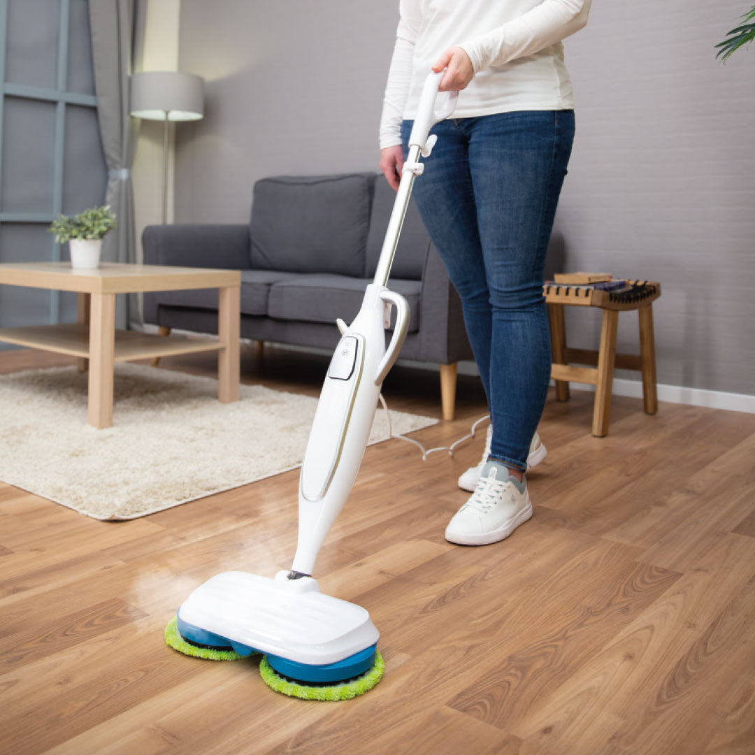Eine Frau reinigt den Holzboden im Wohnzimmer mit dem Dampfbesen Livington Steam Twister.