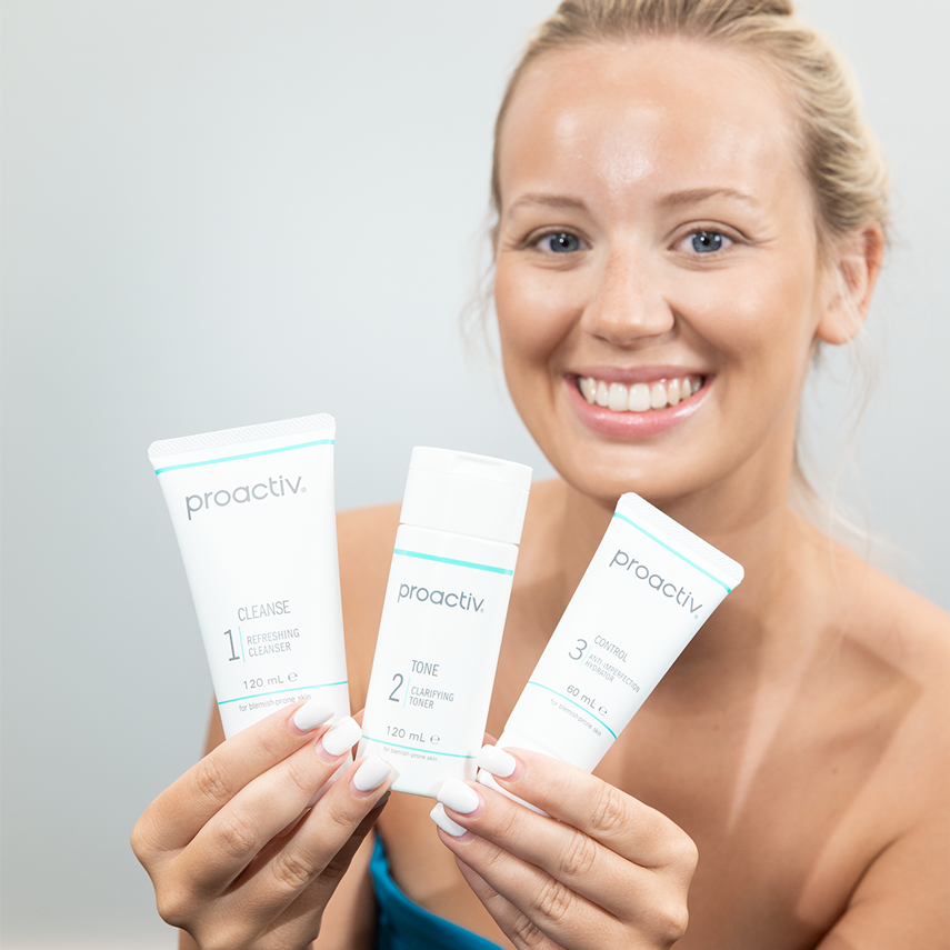 Frau zeigt drei Produkte von Proactiv Solution – Reinigung, Toner und Pflege in einem Komplettsystem.