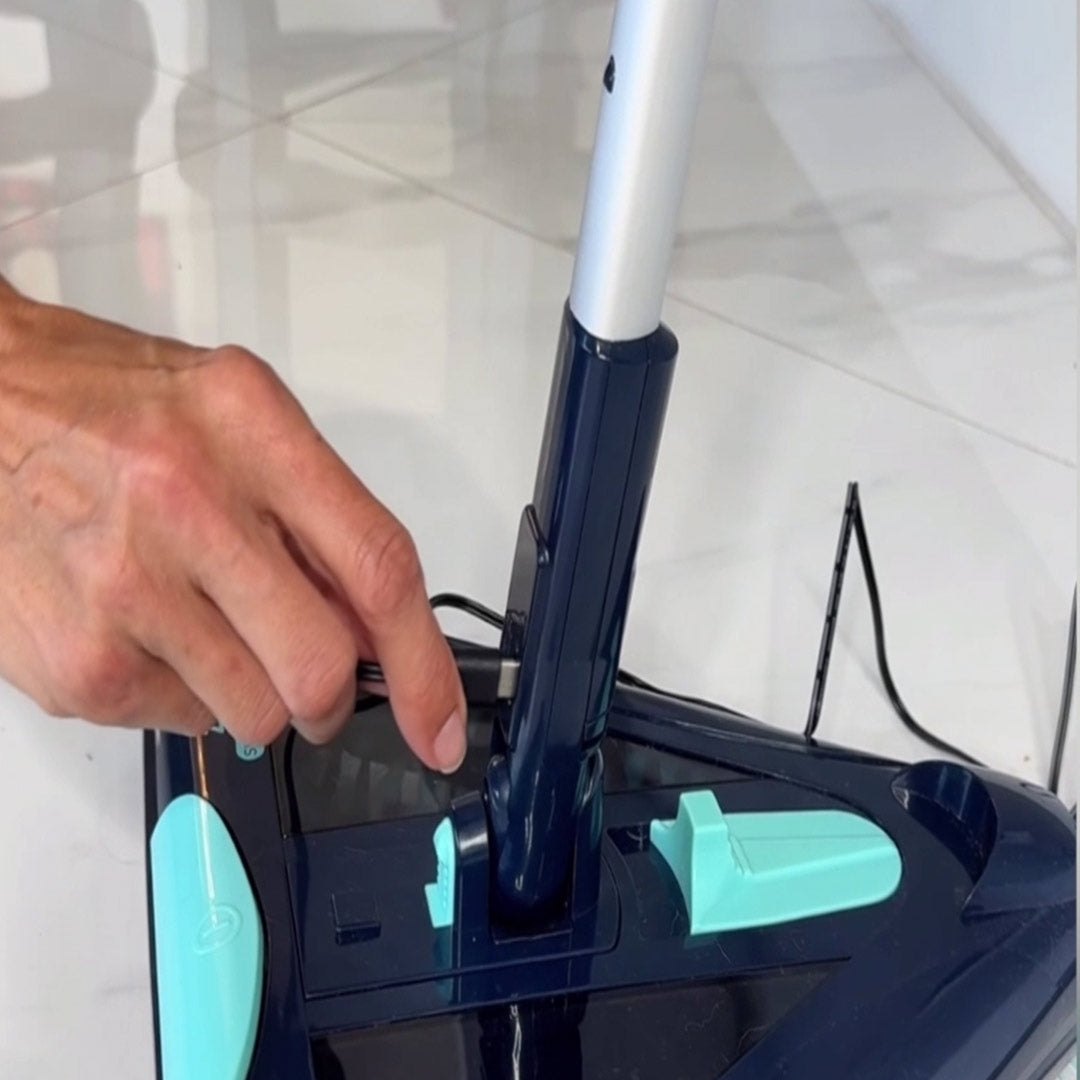 Eine Hand steckt das Ladekabel eines dreieckigen Bodenreiniger in den Akku.