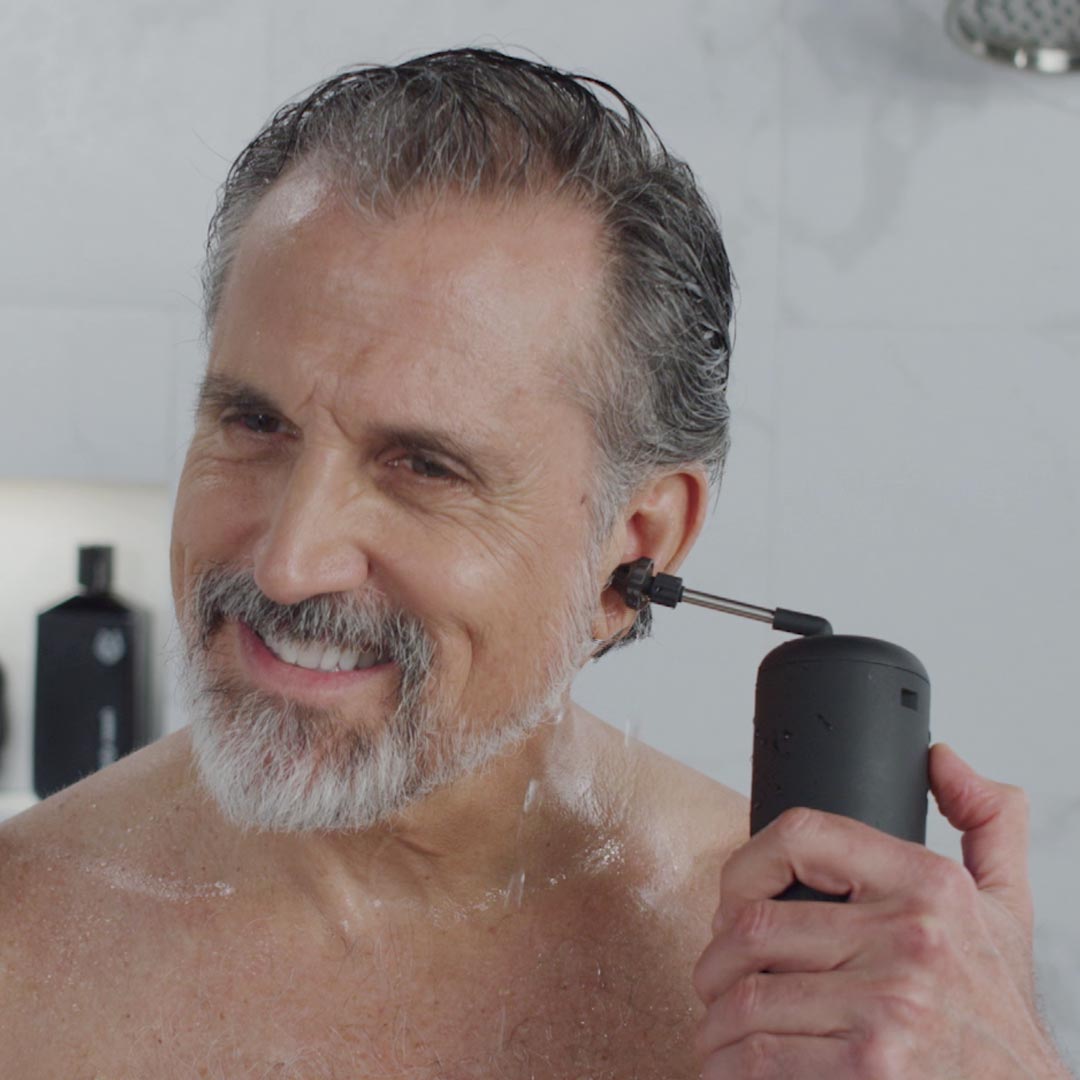 Mann reinigt sein Ohr unter der Dusche mit dem Wush – sanfte und effektive Ohrreinigung mit Wasserstrahl.