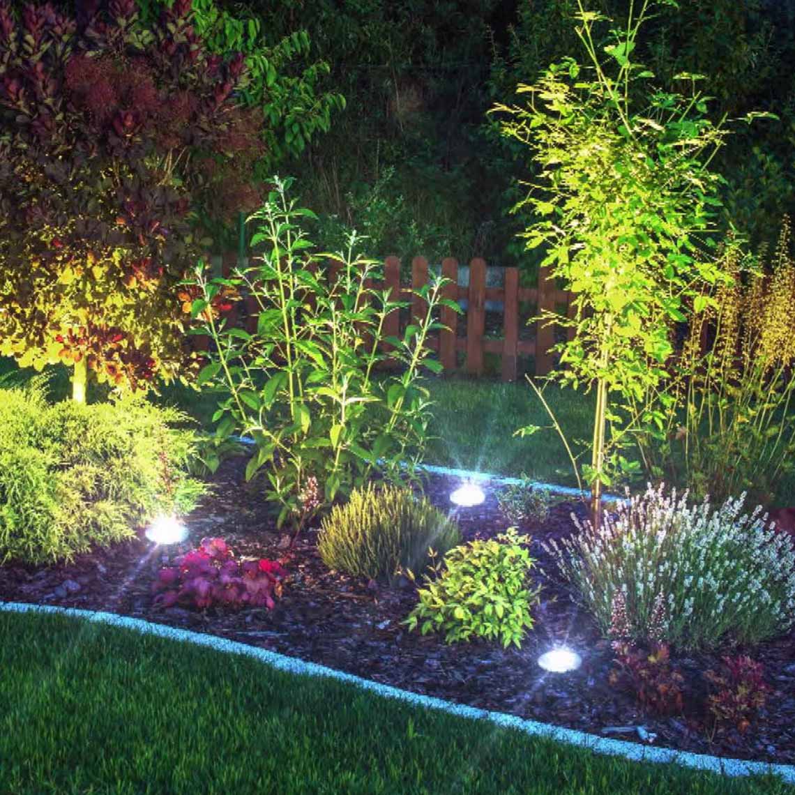 Disk Lights Stone sorgen für dekorative Beleuchtung zwischen Sträuchern und Beeten im Garten.