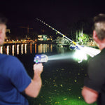 Nachtangeln mit beleuchteter Angelrute und starker LED-Lampe am Wasser