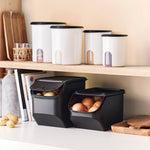 Kartoffeln und Zwiebeln in schwarzen Tupperware OnionSmart Behältern unter einem Küchenregal.