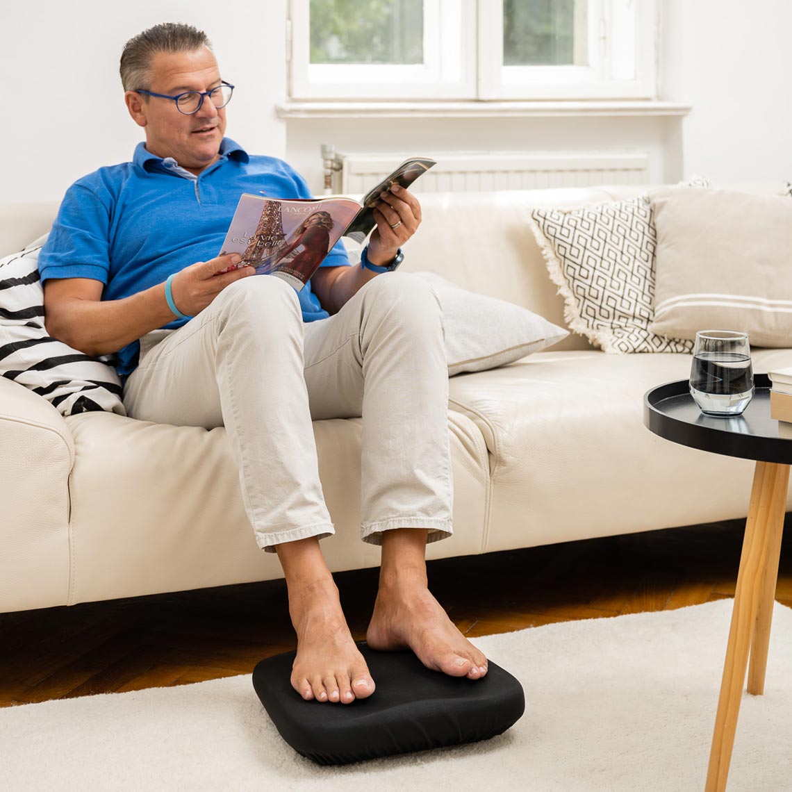 Ein Mann entspannt sich beim Lesen, während der Hammersmith Belena Active Pro die Beine stimuliert.