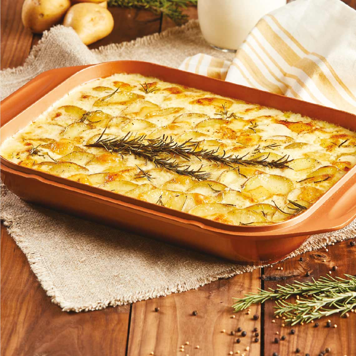 Livington Copperline WonderCooker – Kartoffelgratin mit Rosmarin in kupferfarbener Auflaufform auf Holztisch.