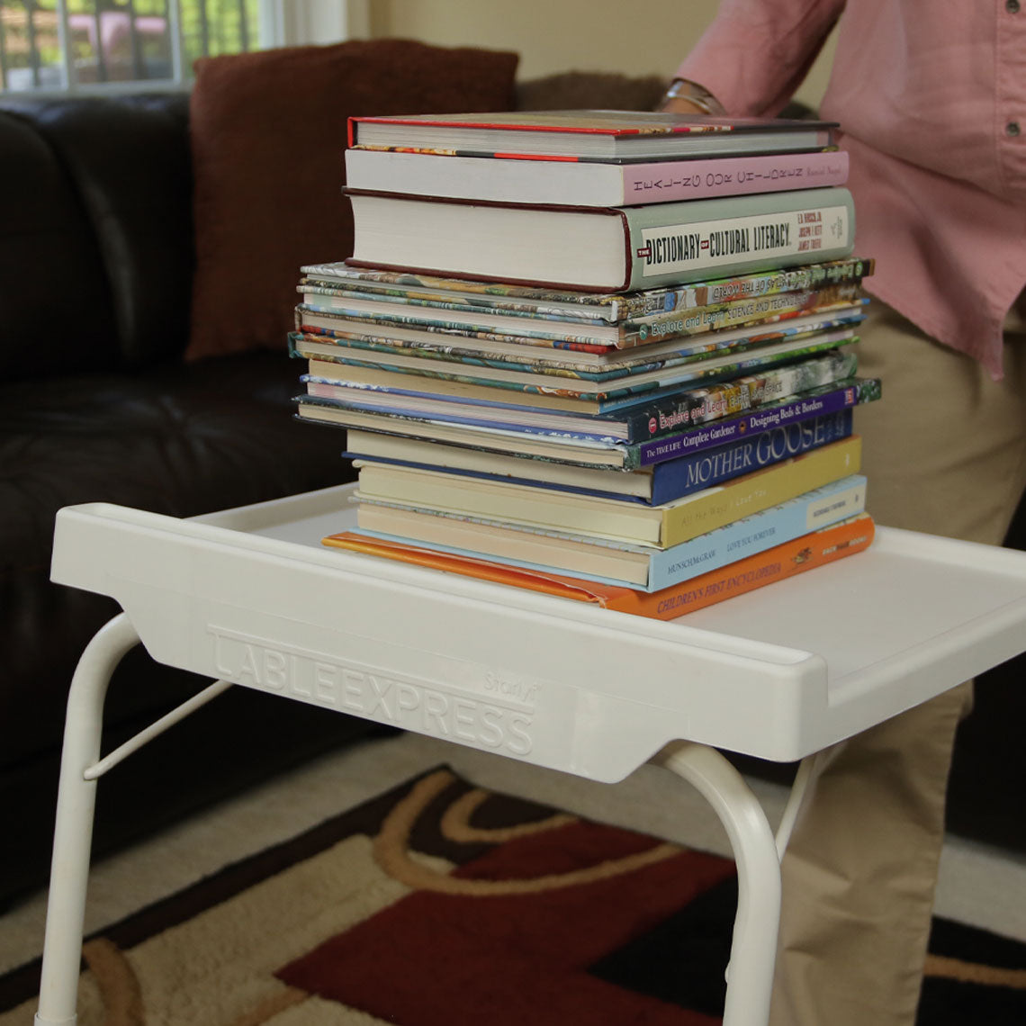 Starlyf Table Express trägt einen hohen Bücherstapel – stabil und belastbar im Alltag.