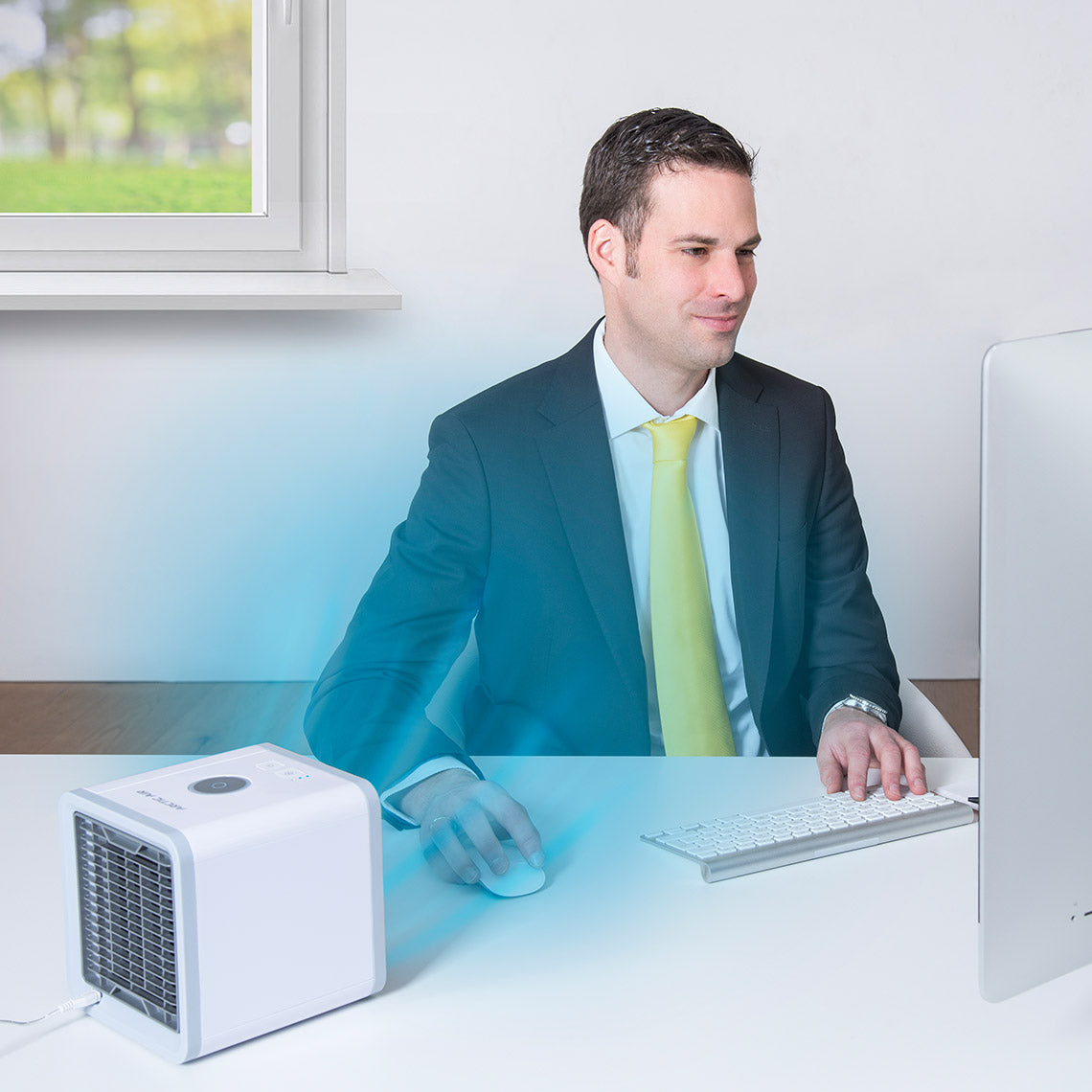 Mann im Anzug arbeitet am PC, der Livington Arctic Air sorgt am Schreibtisch für frische, kühle Luft.