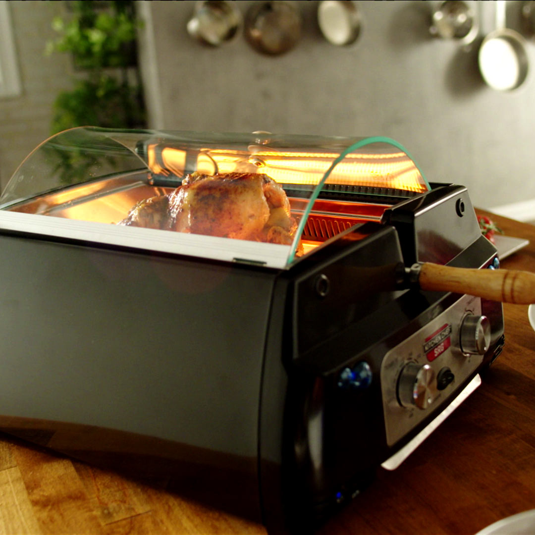 Ein Brathähnchen wird im geschlossenen Rotisserie Chef zubereitet.