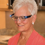 Eine Frau mit Kurzhaarfrisur trägt eine beleuchtete Brille mit LED-Lichtern an den Seiten.