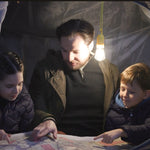 LED-Lampe hängt im Zelt und beleuchtet Familie