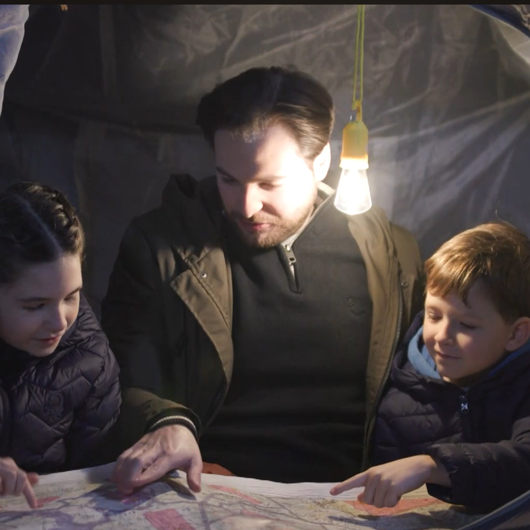 LED-Lampe hängt im Zelt und beleuchtet Familie