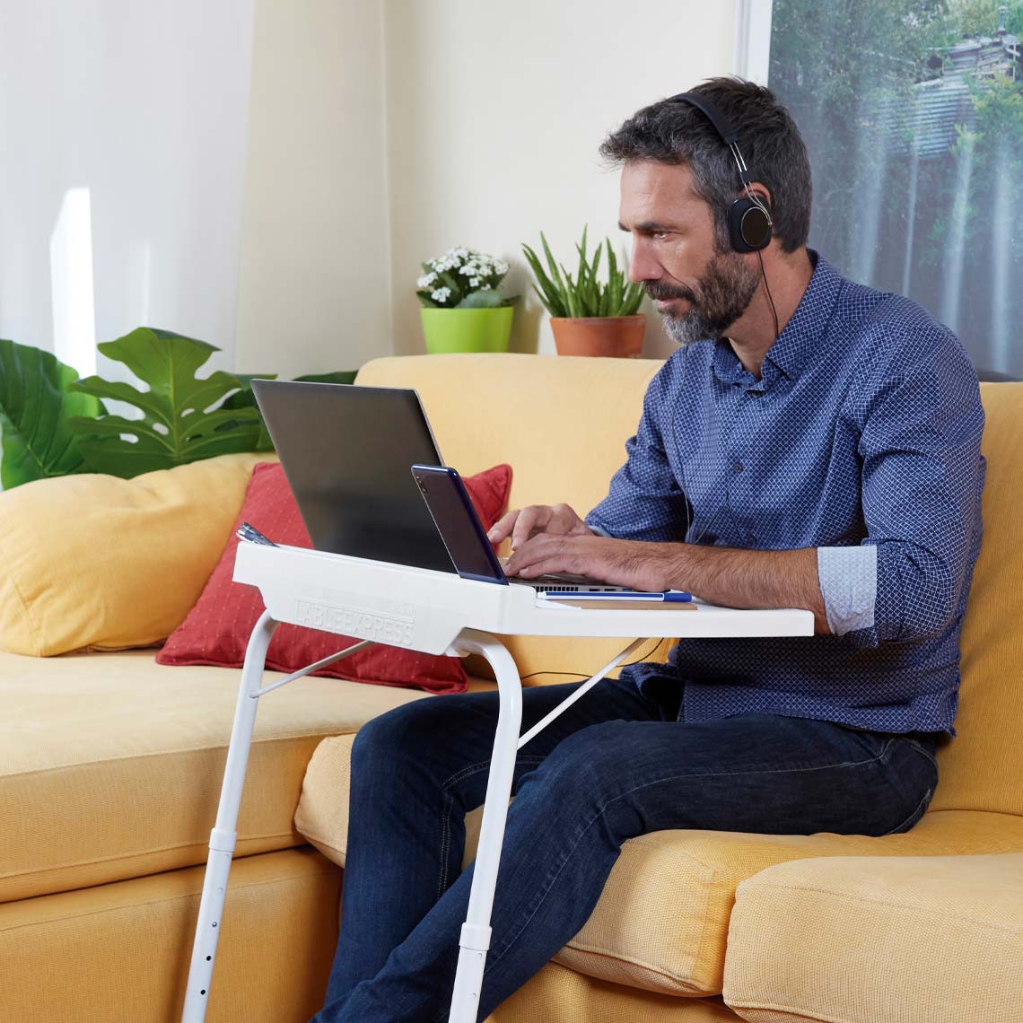 Starlyf Table Express dient als kompakter Arbeitstisch für Laptop und Smartphone auf dem Sofa.
