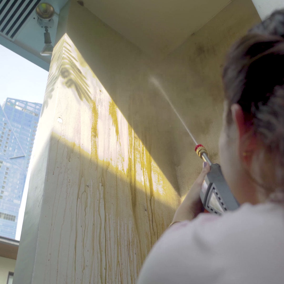 Frau reinigt eine schmutzige Wand im Außenbereich mit dem Hammersmith HydroBlast.