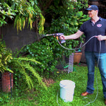 Mann bewässert Pflanzen im Garten mit dem Hammersmith HydroBlast aus einem Eimer.