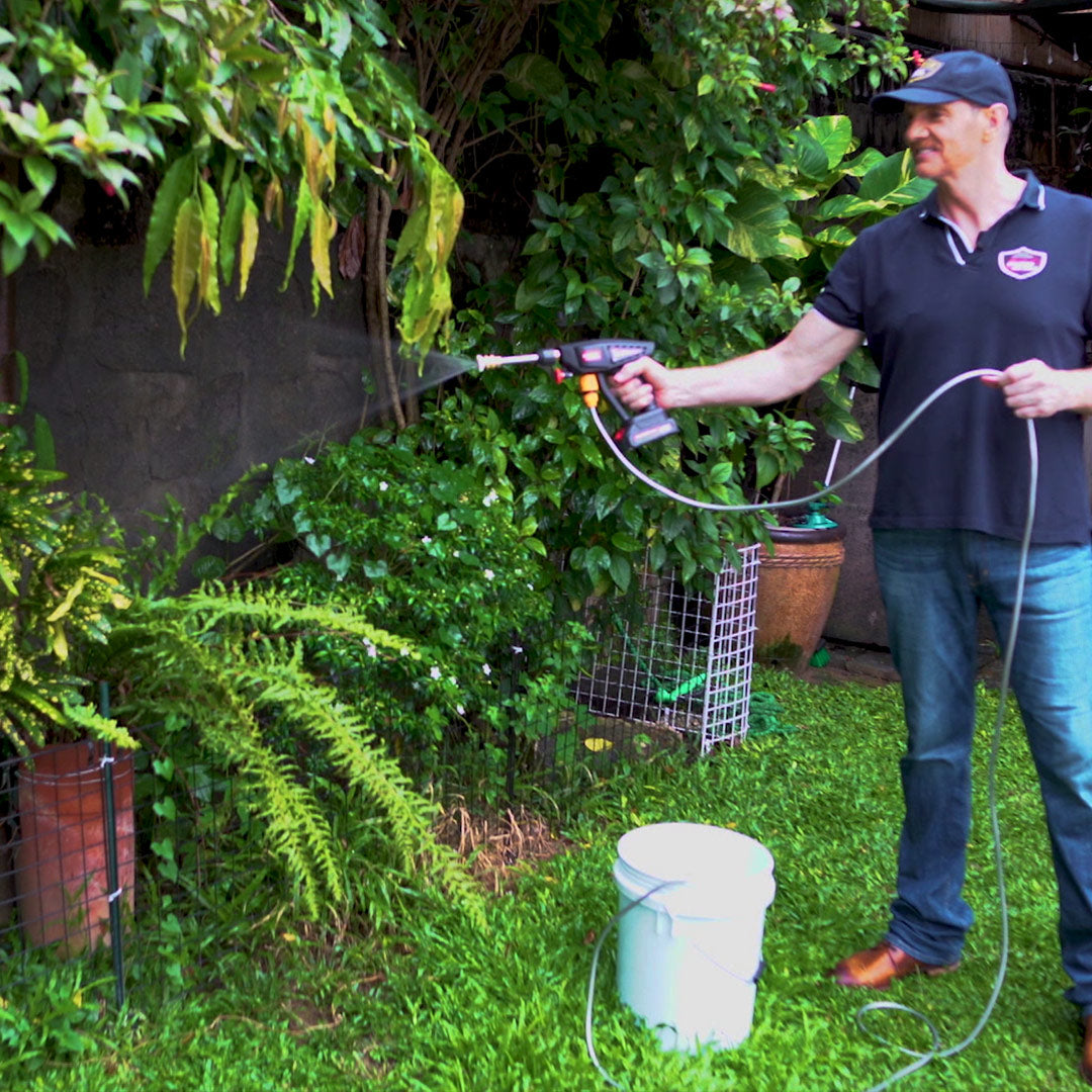 Mann bewässert Pflanzen im Garten mit dem Hammersmith HydroBlast aus einem Eimer.