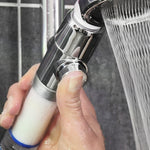 Hand betätigt den Druckknopf am Aquadon EcoTornado Duschkopf – kraftvoller Wasserstrahl sichtbar.