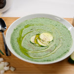 Teller mit Zuchinicremsuppe, garniert mit Olivenöl.