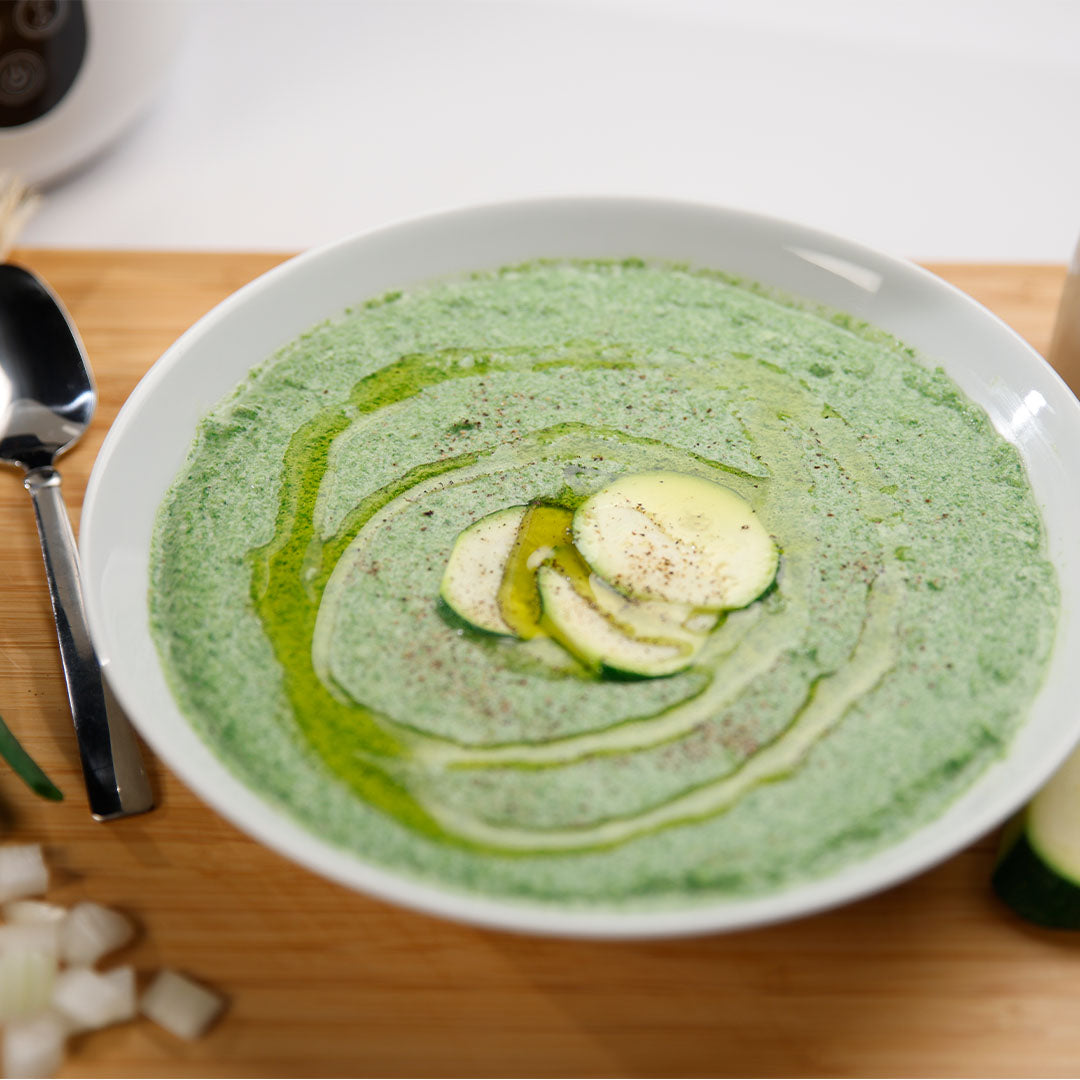 Teller mit Zuchinicremsuppe, garniert mit Olivenöl.