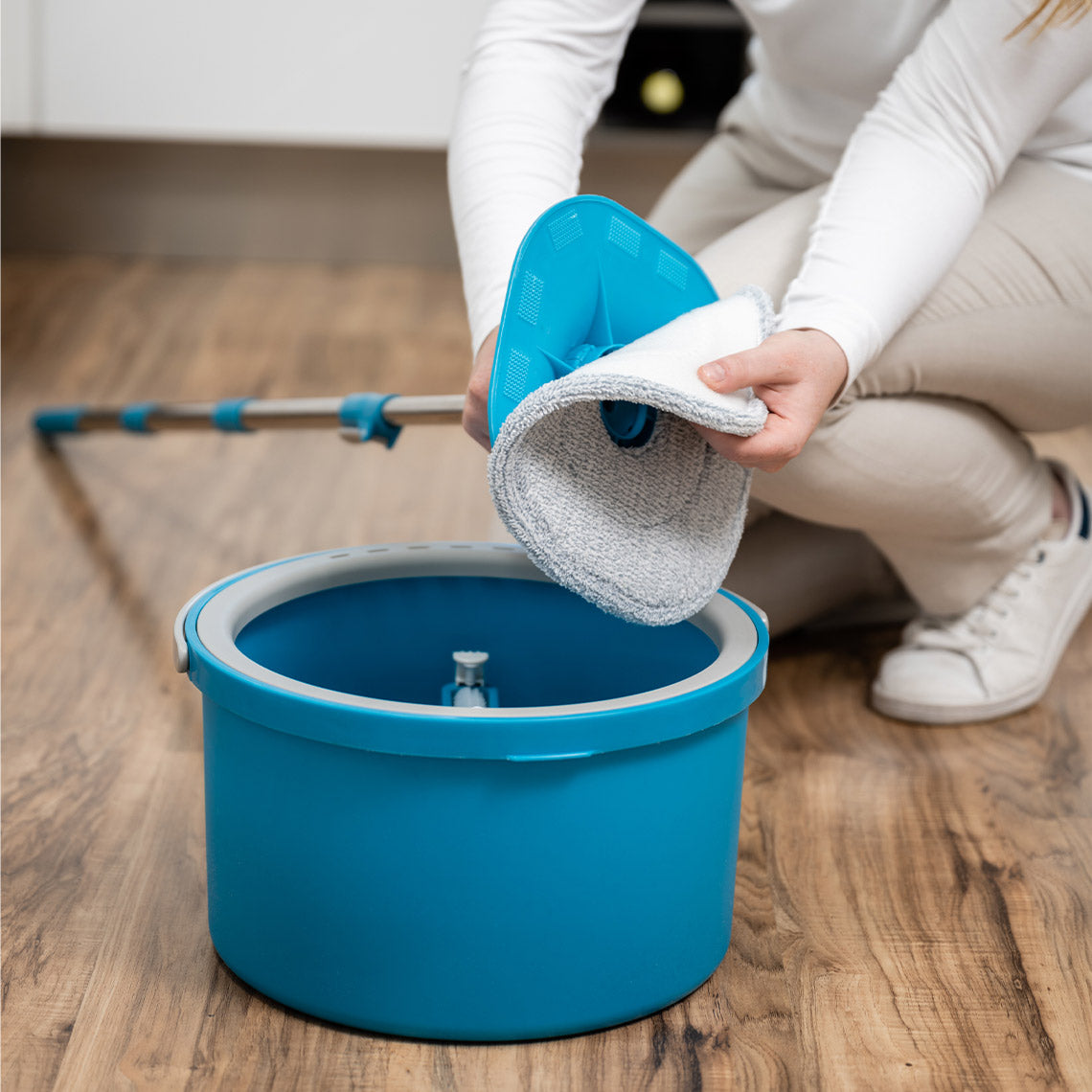 Frau setzt den Mop-Kopf des Livington Clean Water Spin Mop in den Eimer auf Holzboden ein.