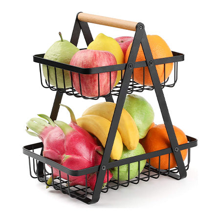Zweistöckiger schwarzer Metallkorb mit Holzgriff, gefüllt mit Obst, freistehend auf weißem Hintergrund.