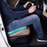 Person sitzt im Auto auf einem Sitzkissen, das den Fahrkomfort verbessert.