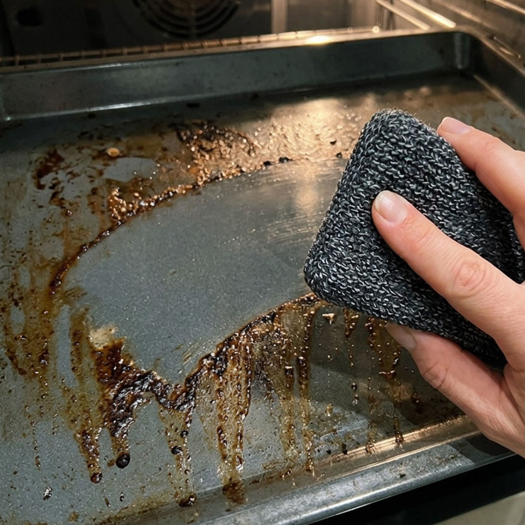 Eine Hand reinigt mit dem Livington ForeverSponge Putzschwamm ein stark eingebranntes Backblech im Ofen und hinterlässt eine saubere Fläche.