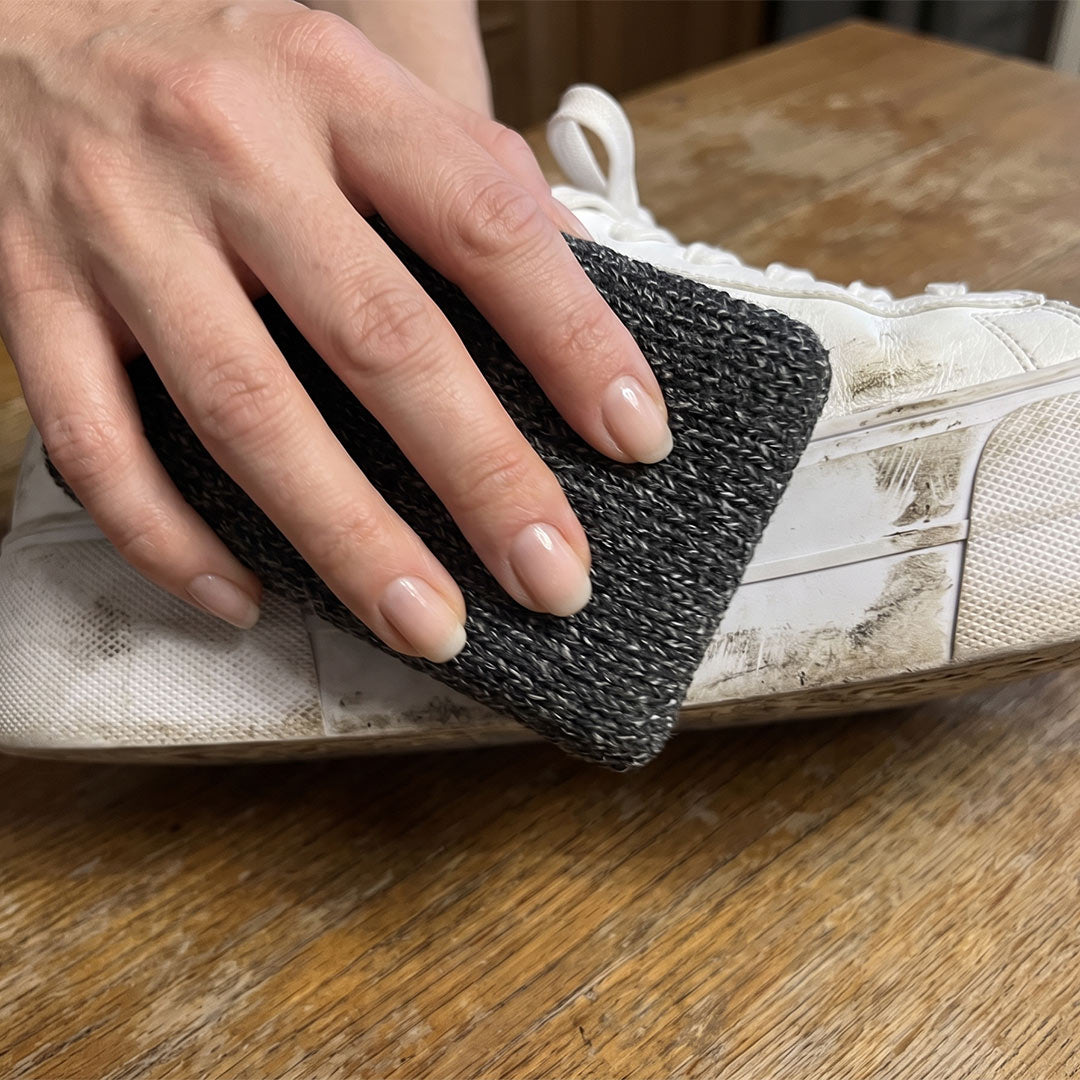 Eine Hand reinigt mit dem Livington ForeverSponge Putzschwamm die schmutzige weiße Sohle eines Sneakers.