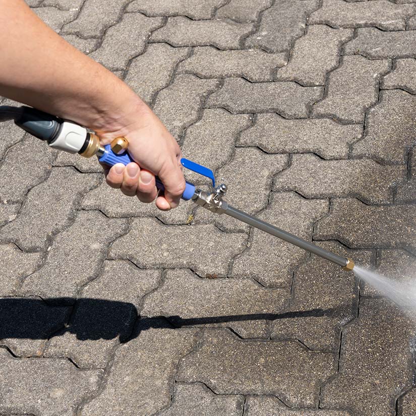 Ein Reinigungsaufsatz mit Hochdruckstrahl wird zur Reinigung von Pflastersteinen verwendet.