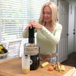 Frau bereitet mit dem Starlyf Cleaning Juicer frischen Saft aus Ananas und Ingwer zu.