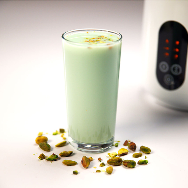Ein Glas Pistaziendrink, daneben liegen geschälte Pistazien. 