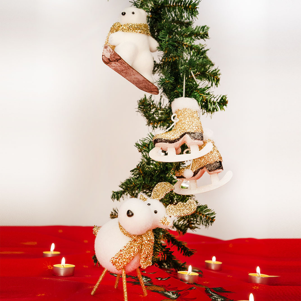 Drei weihnachtliche Deko-Anhänger (Eisbär, Schlittschuh, Rentier) hängen an einem Tannenzweig.