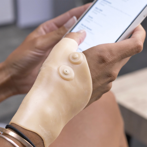 Magnet-Handgelenkbandage an Frauenhand, die ein Handy hält