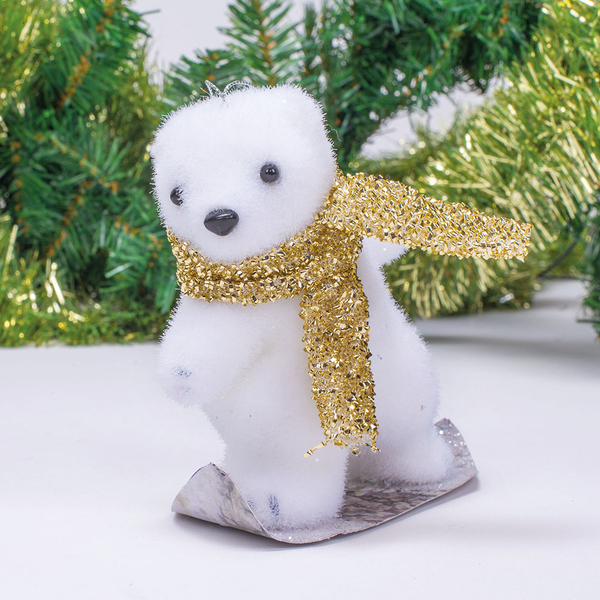 Ein weißer Eisbär mit goldenem Schal steht auf Schlittschuhen vor weihnachtlichem Tannenschmuck.