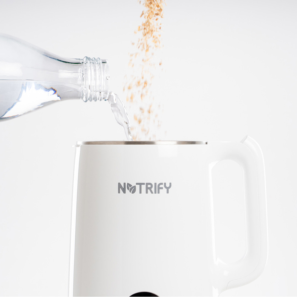 Wasser und Getreide werden in einen weißen Pflanzendrink‑Maker der Marke Notrify eingefüllt