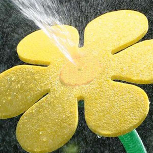 Gelber Rasensprinkler in Blumenform sprüht Wasser nach oben.
