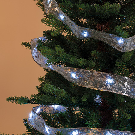 Detailansicht eines geschmückten Weihnachtsbaums mit beleuchtetem, transparentem Band zwischen den Zweigen.