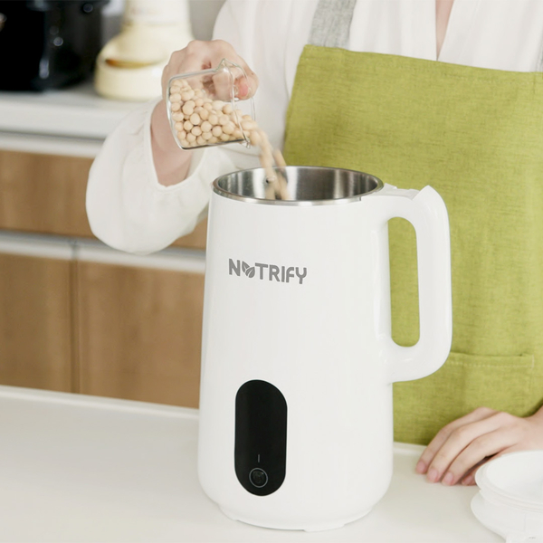 Sojabohnen werden in einen weißen Pflanzendrink‑Maker der Marke Notrify eingefüllt.