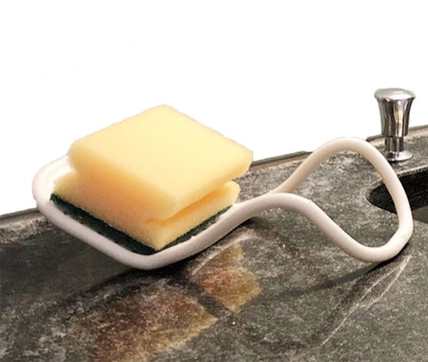 Flexibler weißer Schwammhalter liegt am Spülbeckenrand, darauf ein Reinigungsschwamm ordentlich abgelegt.