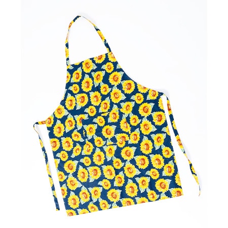 Ausgebreitete Küchenschürze mit vielen gelben Sonnenblumen auf dunklem Hintergrund