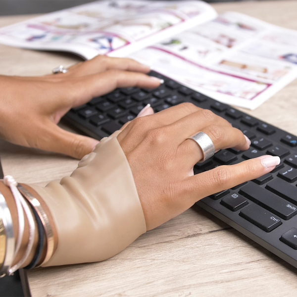 Magnet-Handgelenkbandage an Frauenhand, beim Tippen auf einer Tastatur