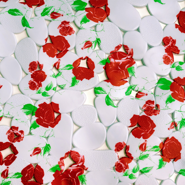 Detailansicht einer Badewannenmatte mit weißen Elementen und rotem Blumenmuster.