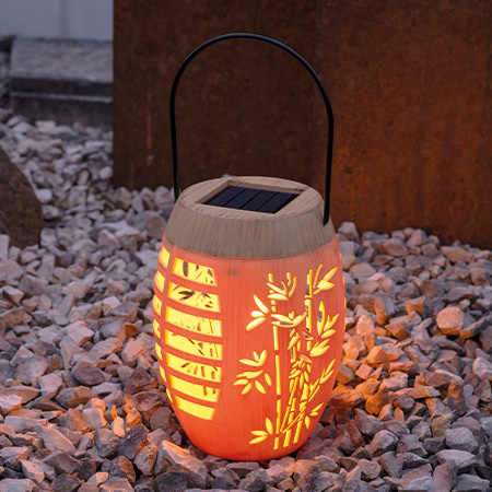 Stimmungsvoller Lichtschein der LED-Solarleuchte in der Dämmerung in einem Kiesbett.